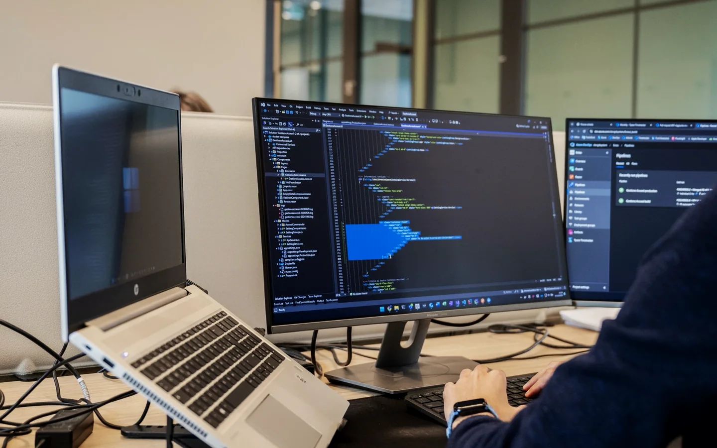 Postazione di sviluppo con il codice di un progetto aperto in Visual Studio e le pipeline su Azure DevOps